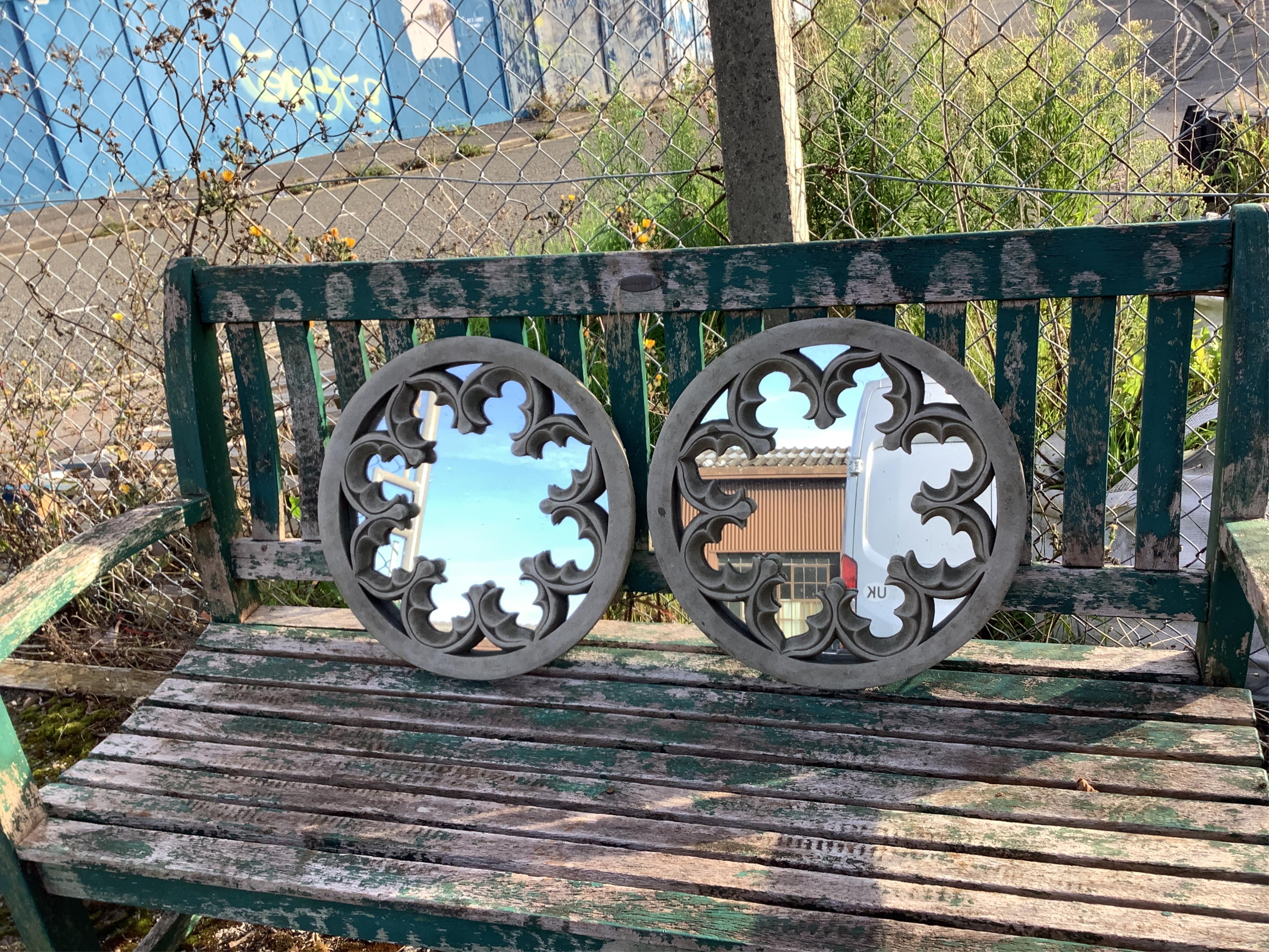 A pair of reconstituted stone wall mirrors of Gothic roundel form, diameter 44cm. Condition - weathered, otherwise good